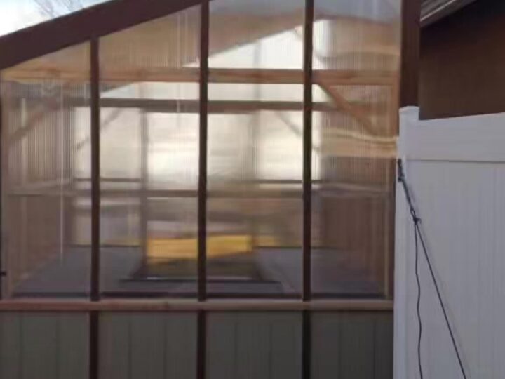 A lean-to greenhouse with polycarbonate glazing built against a house wall