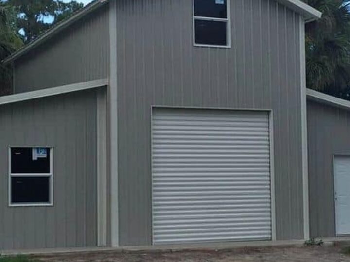 A grey steel garage and shop building with a white roll-up door