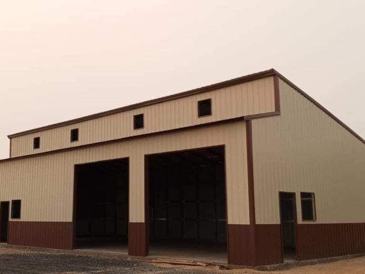 A large tan and burgundy steel shop building with tall equipment bay doors